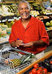 Senior African American man shopping for groceries, with list in hand and pineapple in his shopping cart