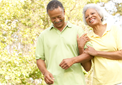 African American woman and man walking arm-in-arm outside, laughing