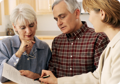 Senior woman and man reviewing finances with a woman who is holding a paper and pen