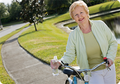 Senior woman smiling as she walks her bike along a path